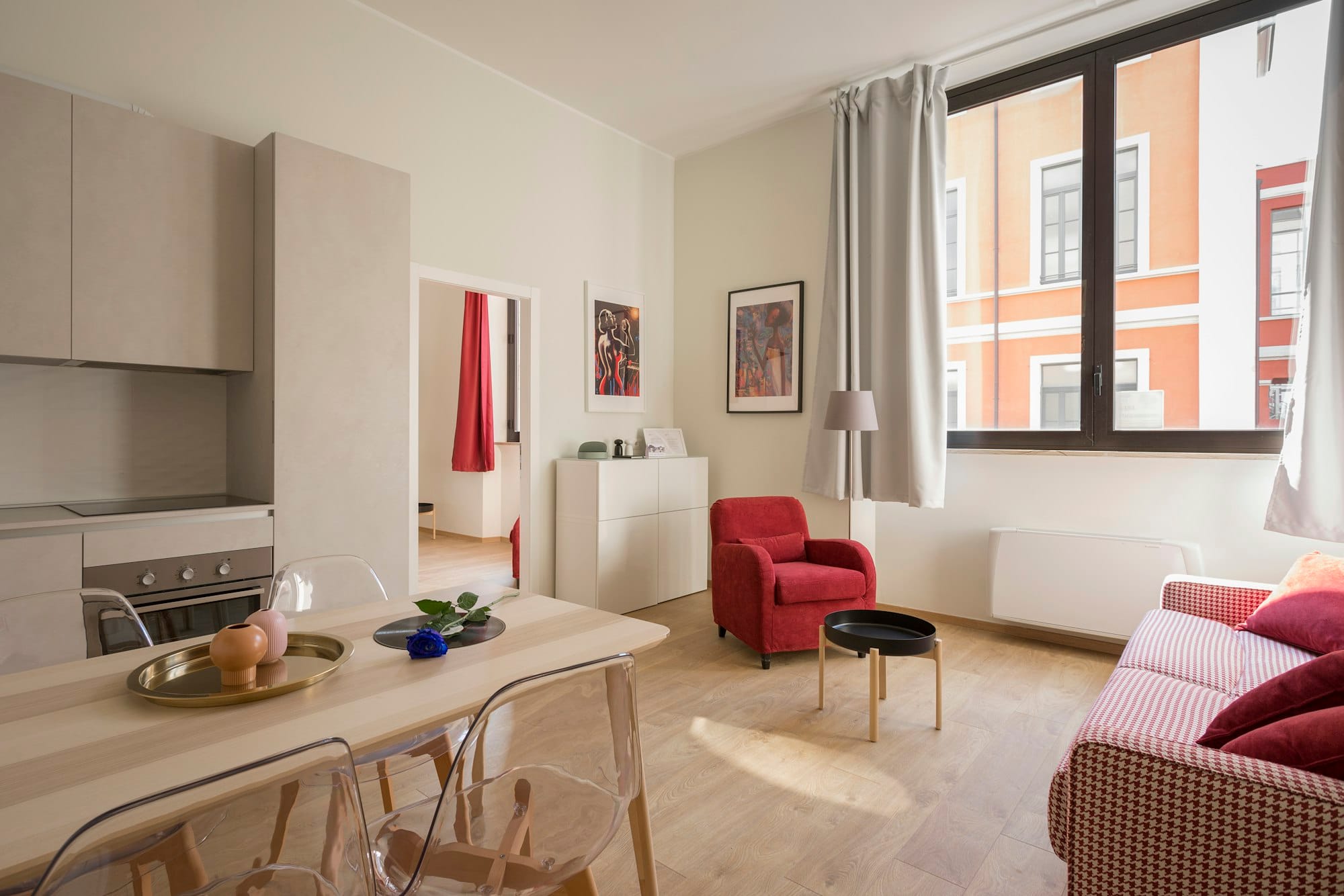 A pale, carefully styled apartment interior with a single red armchair.