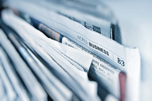 A stack of folded newspapers, the world business section on top.
